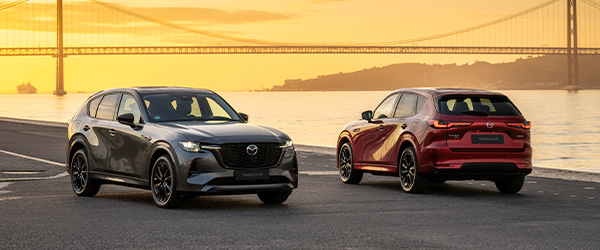 Twee crossovers van Mazda bij zonsondergang, aan het water